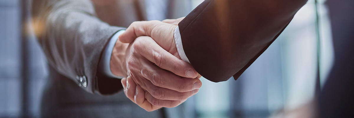 Two men in suits shaking hands.